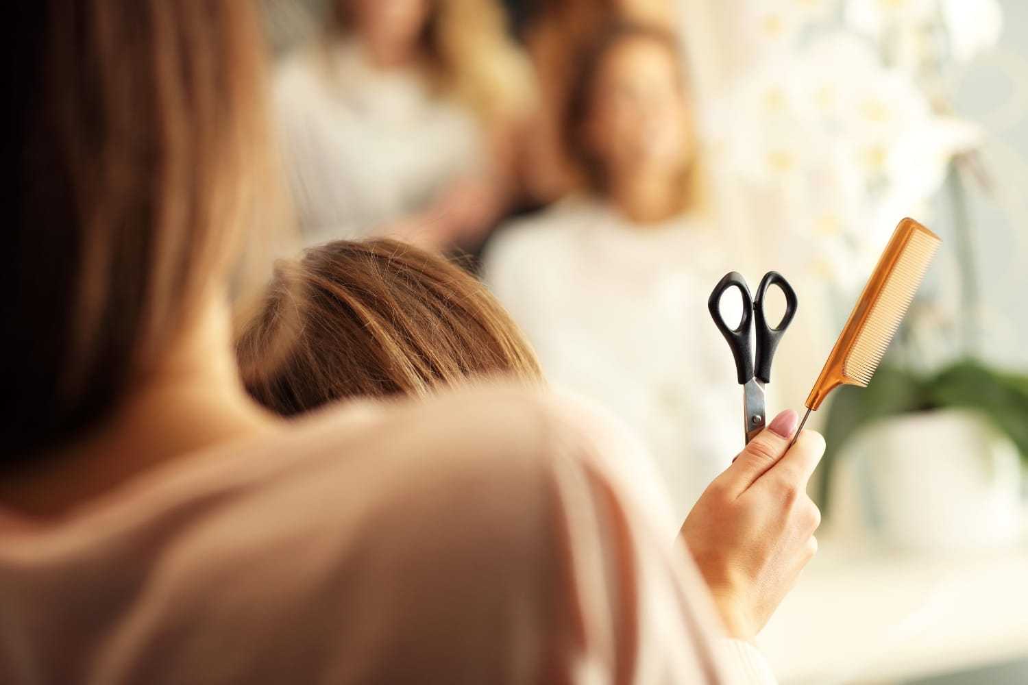 Hairdresser ready to cut client's hair with scissors and comb.
